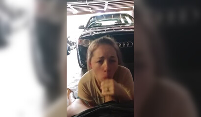 Blonde suce dans le garage près de la voiture