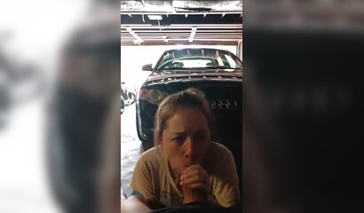 Blonde suce dans le garage près de la voiture