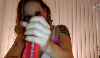 Inked babe sucks a huge red dildo while smoking